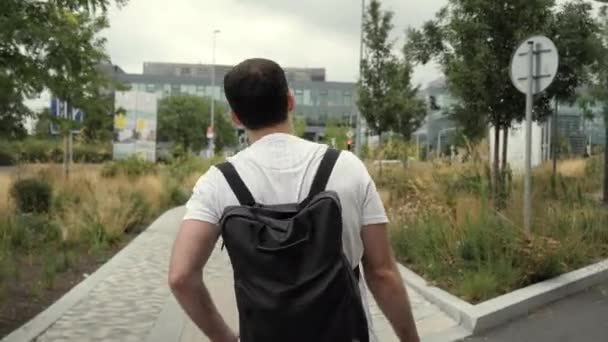 Homme caucasien adulte avec sac à dos marchant dans la rue en ville à l'extérieur . — Video
