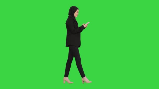 Femme en hijab à l'aide d'un téléphone mobile marchant sur un écran vert, Chroma Key .