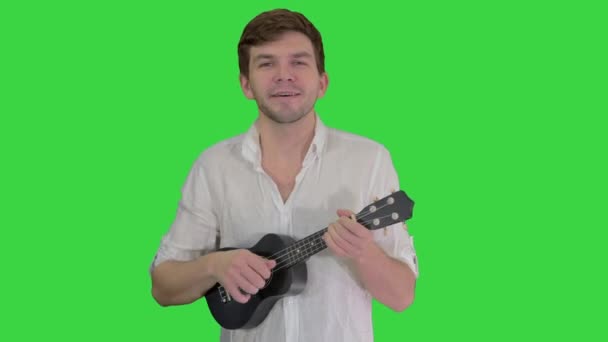 Man med ukulele sjunger en sång på en grön skärm, Chroma Key. — Stockvideo