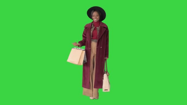 Великолепная женщина в шляпе позирует с пакетами для покупок, улыбаясь на зеленом экране, Chroma Key . — стоковое видео