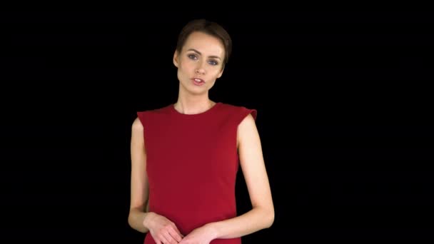 Зачарована красива молода жінка в червоному платті розмовляє з камерою Альфа Канал. — стокове відео