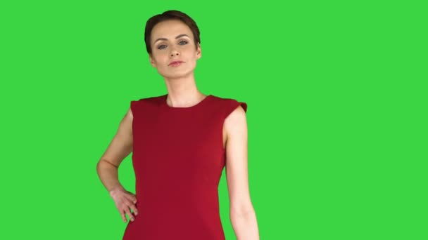 Mooie jonge vrouw met kort haar in rode jurk poseren op een groen scherm, Chroma Key. — Stockvideo