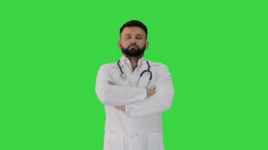 Genç beyaz erkek doktor, elleri katlı bir şekilde yeşil ekranda duruyor, Chroma Key.