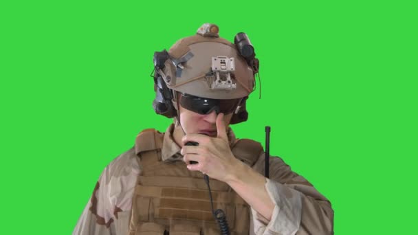 Joven soldado camina, sostiene una estación de radio y da órdenes en una pantalla verde, Chroma Key . — Vídeos de Stock