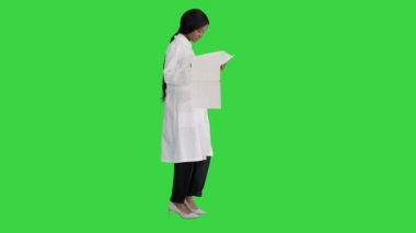 Yeşil Ekran, Chroma Key 'de yürüyen ve kardiyogram kayıtlarına bakan Afro-Amerikalı doktor kadın..