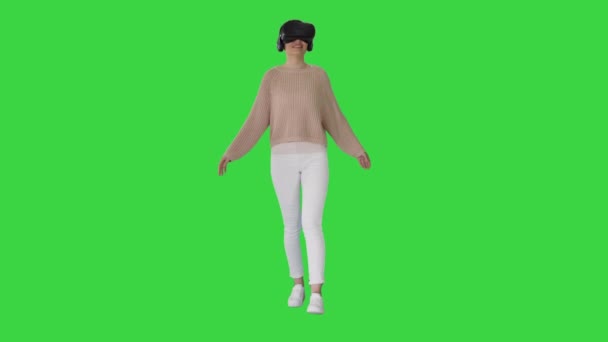 초록색 화면 위를 걷고 있는 VR 가상 현실 헤드셋을 사용하는 여성, 크롬 키. — 비디오