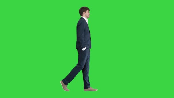 Knappe zakenman loopt met zijn handen in de zakken op een groen scherm, Chroma Key. — Stockvideo