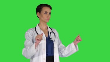 Sağlık, tıp ve teknoloji konsepti - gülümseyen kadın doktor bir şeye işaret ediyor veya yeşil ekrandaki hayali düğmelere basıyor, Chroma Key.