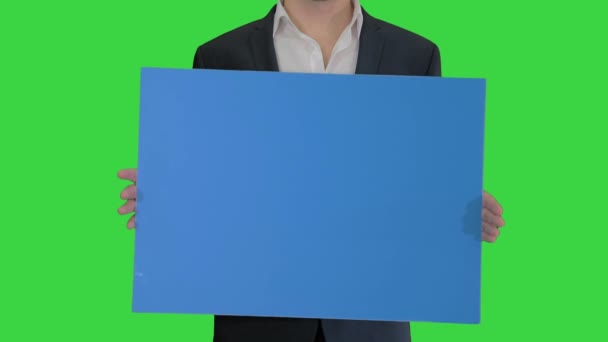 Mann im Anzug hält ein leeres Brett auf einem Green Screen, Chroma Key. — Stockvideo