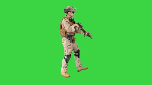 Soldat sätter sig ner för att sikta och skjuta med gevär på en grön skärm, Chroma Key. — Stockvideo