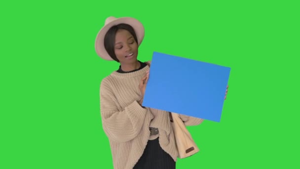 Attraktive junge afrikanisch-amerikanische Frau zeigt und zeigt auf leere Tafel auf einem Green Screen, Chroma Key. — Stockvideo