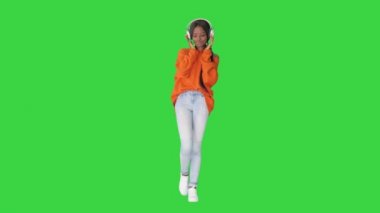 Mutlu, güzel, Afro-Amerikan kadın kulaklıklarıyla müzik dinliyor yeşil ekranda, Chroma Key 'de.