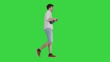 Ukulele çalan genç adam, şarkı söylüyor ve yeşil ekranda yürüyor, Chroma Key.
