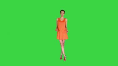 Yeşil Ekran, Chroma Key 'de turuncu elbiseli, şaşırmış ya da şaşırmış genç bir kadın..