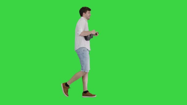 若い男はウクレレを演奏し、緑の画面で歌い、歩く、クロマキー. — ストック動画