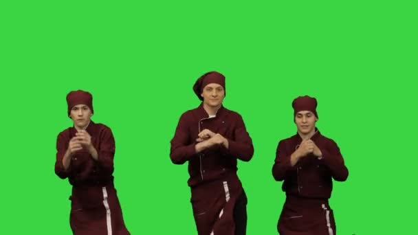 Drie jonge lachende koks dansen op een groen scherm, Chroma Key. — Stockvideo