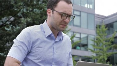 Handsome man working on his laptop outdoors.