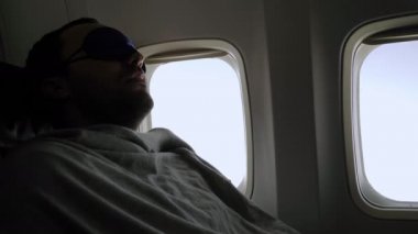 Rest and comfortable flight in the plane. Man in a mask for sleeping.