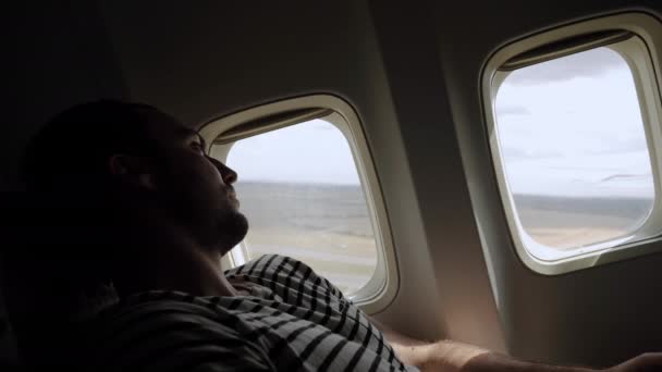 Young man looking in the window of airplane when it takes off. — Stockvideo