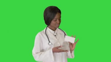 Kadın doktor gülümsüyor ve elinde yeşil ekranda bir kutu ilaç tutuyor, Chroma Key..