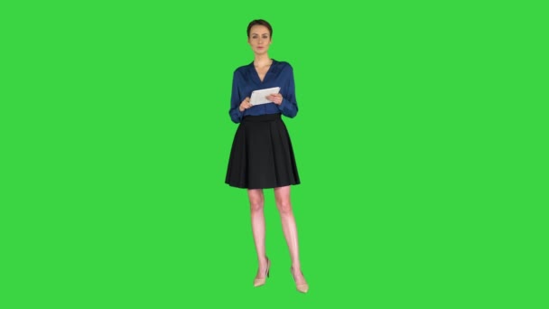 Señora con el pelo corto con ropa formal sosteniendo una tableta en sus manos y hablando con la cámara en una pantalla verde, Chroma Key. — Vídeo de stock