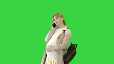 Sırt çantalı hamile kadın telefonda yeşil ekranda konuşuyor, Chroma Key..