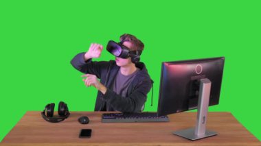 VR kulaklıklı genç adam Yeşil Ekran 'da sanal nesneleri manipüle ediyor, Chroma Key.