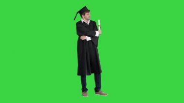 Mezuniyet cüppeli bir adam yeşil ekranda kameraya poz veriyor, Chroma Key.