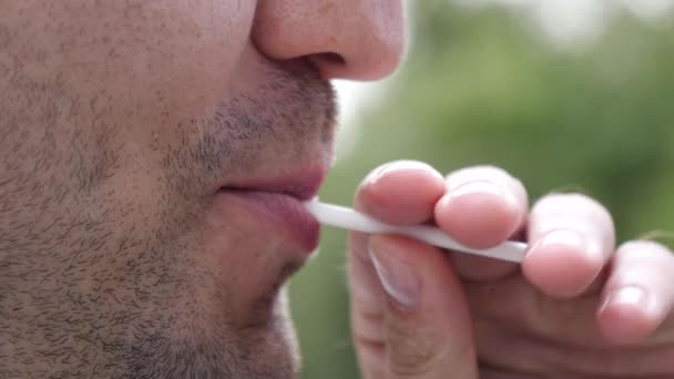 Hombre comiendo piruleta en el parque . — Vídeo de stock