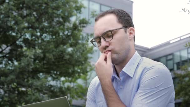 Giovane startupper maschile negli occhiali si è stancato di lavorare sul computer portatile . — Video Stock