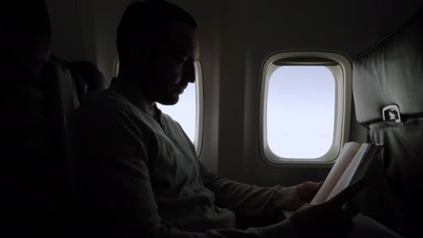 Hombre leyendo libro durante el vuelo . — Vídeos de Stock