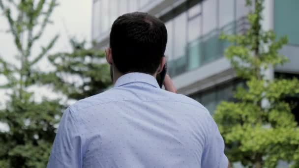 Kaukasisk affärsman går på gatan på kontoret och pratar i telefon. — Stockvideo