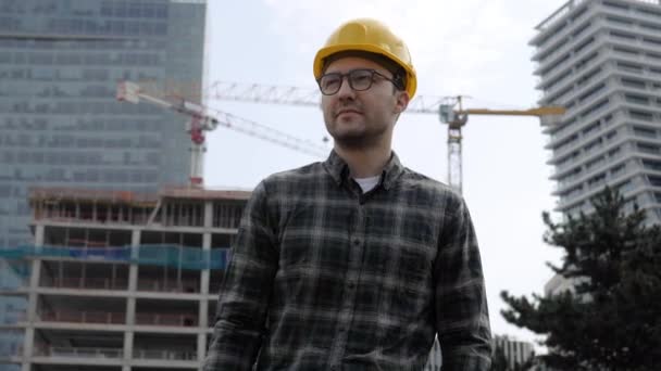 Hombre de arquitecto guapo con sombrero duro caminando desde el sitio de construcción . — Vídeos de Stock