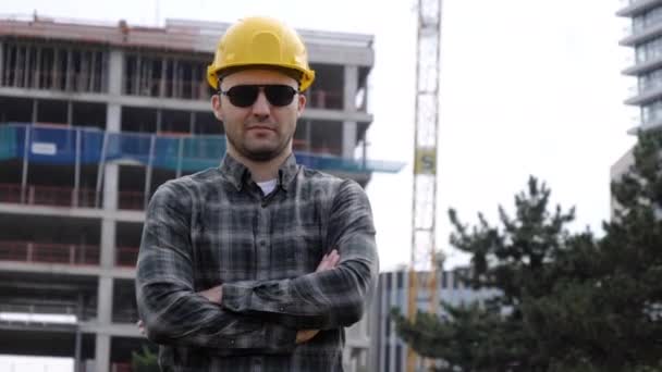 Giovane bell'ingegnere uomo indossa casco di sicurezza in occhiali da sole facendo uno sguardo alla fotocamera . — Video Stock