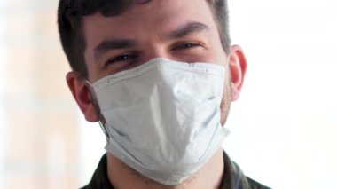 Tıbbi maskeli tatmin olmuş bir adam kameraya bakıyor..