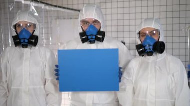 Güvenlik giysileri içindeki bilim adamları boş tahta tutuyorlar..