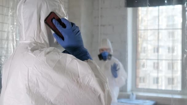 One doctor in protective suit making a serious call while another one in dancing. — Stock Video