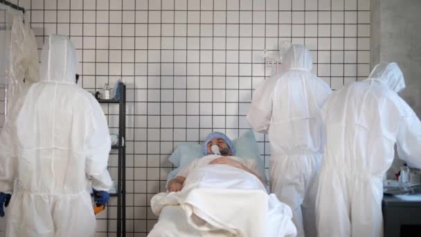 Lékaři v Hazmat sterilní oblek kolem pacienta v nemocnici. — Stock video