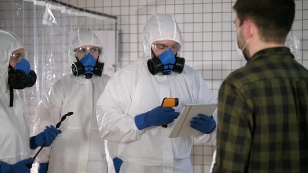 Equipo en trajes protectores medición de temperatura de un civil en un hospital. Coronavirus, COVID-19 — Vídeos de Stock