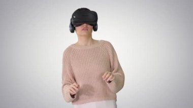 Arkaplanda yürüyen ve etkileşimli VR kulaklık kullanan sevimli genç bir kadın..
