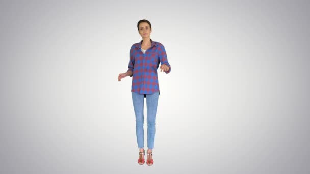 Casual vrouw in denim shirt dansen en kijken naar de camera op gradiënt achtergrond. — Stockvideo