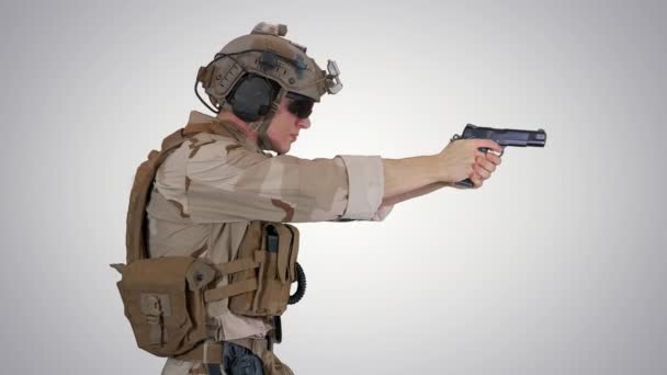 Un soldato delle forze speciali con un casco sulla testa che cammina e spara da pistola a mano su sfondo sfumato . — Video Stock