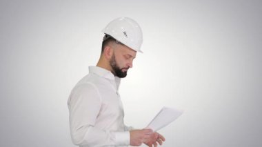 Erkek mühendis sabit bir şapkayla yürüyor ve gradyan arka plandaki belgelere bakıyor..