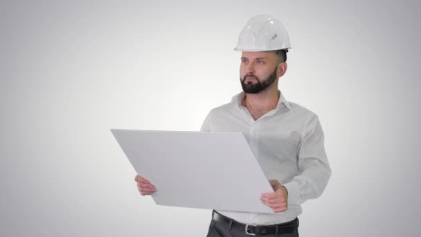 Ingeniero hombre caminando en casco mirando el proyecto de reconstrucción sobre fondo de gradiente . — Vídeos de Stock