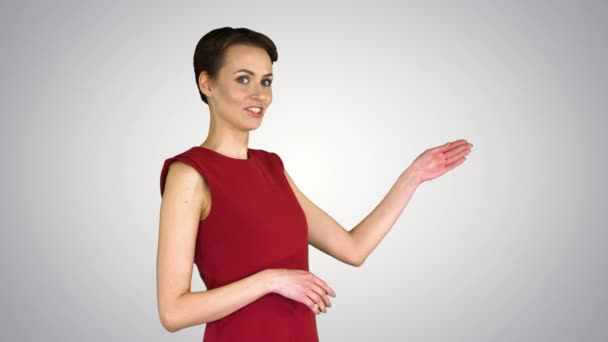 Ładna kobieta w sukience rozmawiająca i wykonująca gesty jak w prognozie pogody na tle gradientowym. — Wideo stockowe