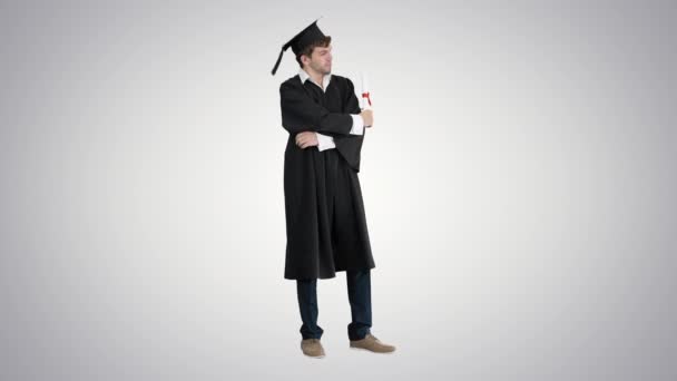 Uomo in abito di laurea in posa per la fotocamera su sfondo sfumato . — Video Stock