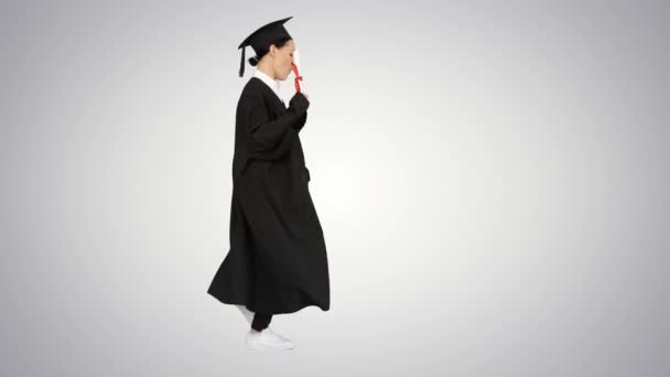 Mujer caucásica en bata de graduación bailando caminando sobre fondo degradado . — Vídeos de Stock