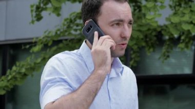 Yakışıklı genç adam telefonda yürüyor ve konuşuyor..