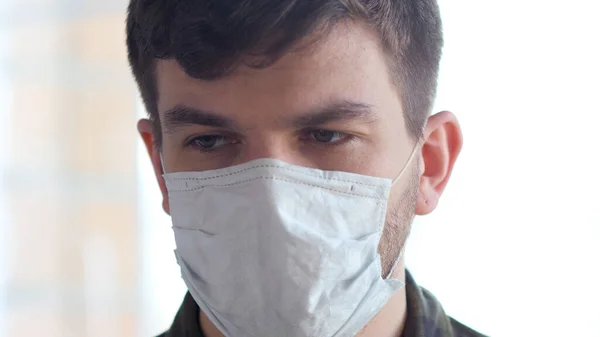 Hombre joven con máscara de gripe médica con miedo a la epidemia COVID-19 . — Foto de Stock