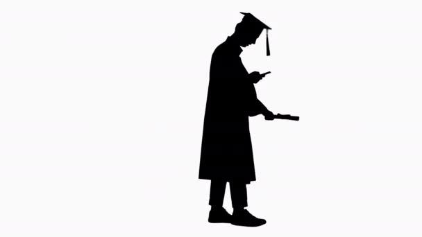 Silhouette卒業:彼の携帯電話で幸せな学生の歩行とテキストメッセージ. — ストック動画